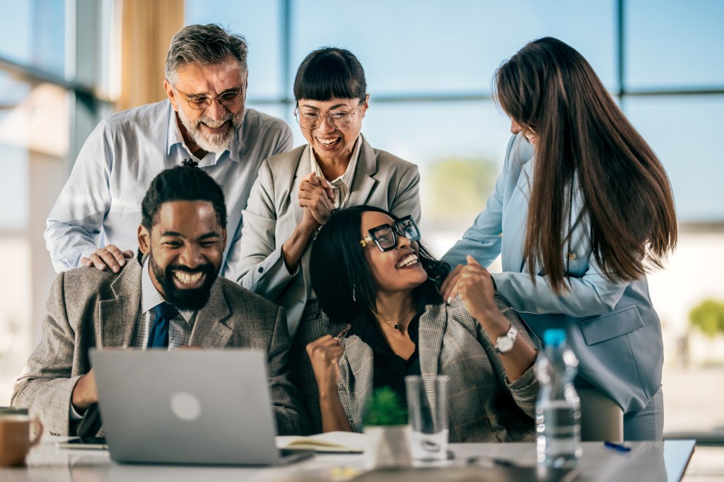 Shot of multi-ethnic business team raising hands to showing happiness from their achievements.